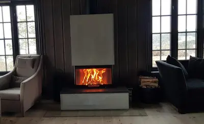 a fireplace in a living room with a fire in it at Mjøshytte in Stange