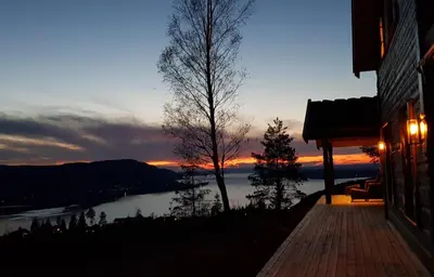 a building with a view of a lake at sunset at Mjøshytte in Stange