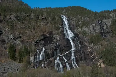 a waterfall on the side of a mountain at Trolltunga Odda Apartments in Odda