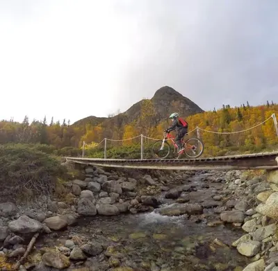 a person riding a bike on a bridge over a river at Fjellstova Storehorn Apartments in Torset