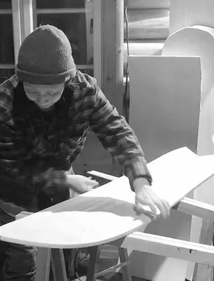 a man is cutting a piece of paper on a table at Fjellstova Storehorn Apartments in Torset