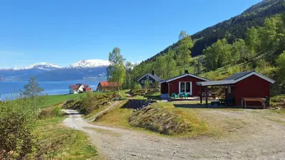 a house on the side of a hill next to a road at Nordfjordcabins RED in Utvik