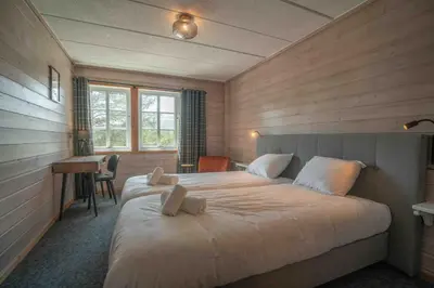 a bedroom with a large bed and a desk at Pollfoss Boutique Hotel & Spa in Skjåk