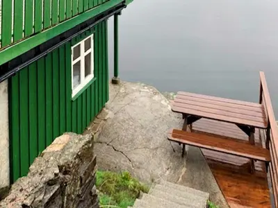 a bench next to a green building with a window at 6 person holiday home in LINDÅS in Lindås