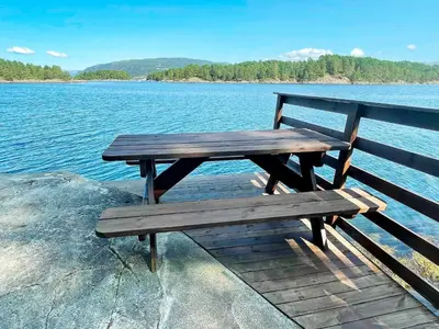 a wooden bench sitting on the edge of a lake at 6 person holiday home in LINDÅS in Lindås