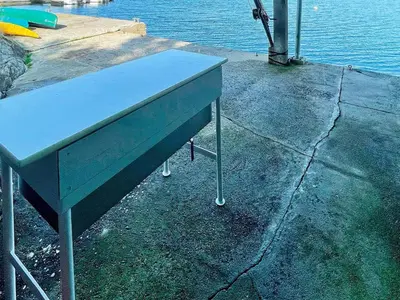 a blue table sitting on the side of the water at 6 person holiday home in LINDÅS in Lindås