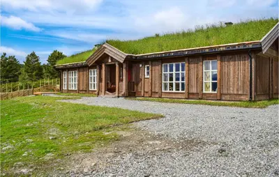 a building with a grass covered roof with a building with a gravel yard at Moltebæret in Skåbu