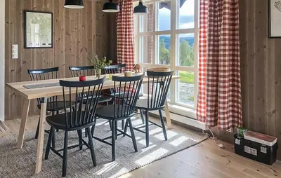 a dining room with a table and chairs and a window at Moltebæret in Skåbu
