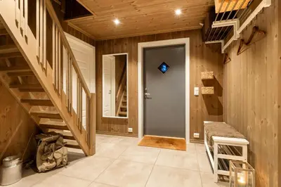 a hallway with wooden walls and a blue door and stairs at Villa Budor - 60 min fra OSL - Jaccuzzi - 4 soverom in Nordset