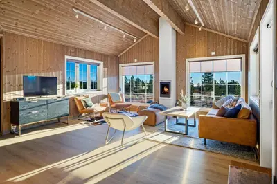 a living room with wooden walls and furniture and windows at Villa Budor - 60 min fra OSL - Jaccuzzi - 4 soverom in Nordset