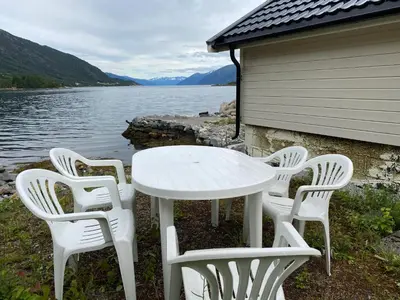 a white table and chairs next to a body of water at Askevika in Vikum