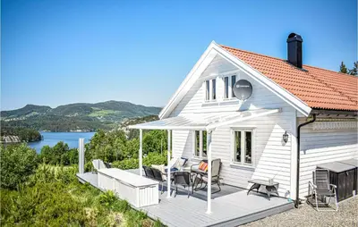 a white house with a deck with chairs at 3 Bedroom Awesome Home In Skjold in Skjold