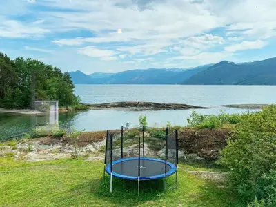 a trampoline in the grass next to a body of water at Seaside Serenity in Hardangerfjord-By Traum in Tyrvikbygd