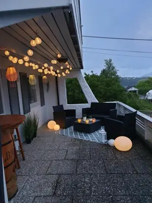 a patio with couches and tables on a house at Bergen Apartment with Fjord View in Isdalsstø