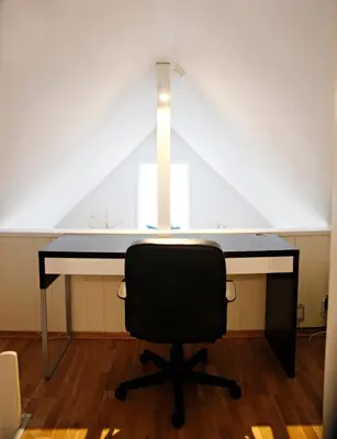a desk with a chair in a room with a roof at Marthas Rorbu in Bakkasund