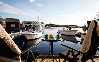 a table and chairs on a dock with boats in the water at Marthas Rorbu in Bakkasund
