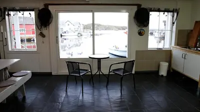 a kitchen with a table and chairs in front of a window at Marthas Rorbu in Bakkasund