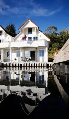 a white house with its reflection in a body of water at Marthas Rorbu in Bakkasund