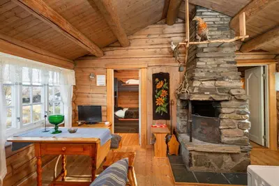 a log cabin living room with a stone fireplace at Besseggen Fjellpark AS in Maurvangen