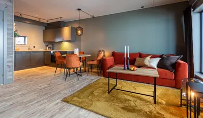 a living room with a red couch and a kitchen at Ridderleiligheter in Beitostøl