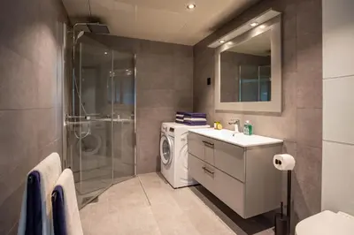 a bathroom with a washing machine and a shower at Ridderleiligheter in Beitostøl