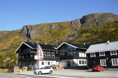 a large black and white building with cars parked in front at Fossheim Lodge - arealeffektiv minileilighet in Torset