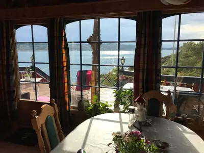 a dining room with a table and a view of the ocean at Ferienhaus „Draumen“ in Norwegen in Bømlo