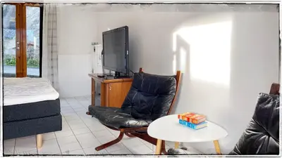 a living room with a black leather chair and a tv at Bergvegen Guesthouse Aalesund in Ålesund