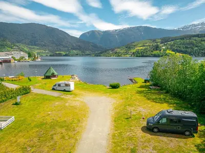 a van parked on a dirt road next to a lake at Ulvik Camping in Ulvik