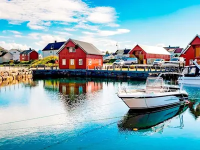 a boat in the water in front of a red house at 7 person holiday home in Bud in Bud