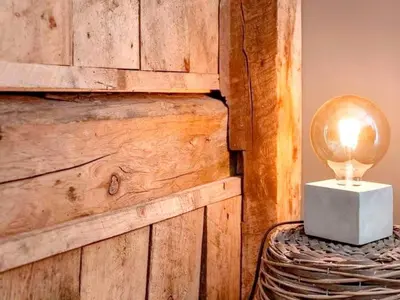 a lamp on a table with a wooden wall at 7 person holiday home in Bud in Bud