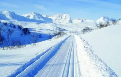 a road covered in snow with mountains in the background at Oppdal Alpintun ski in ski out in Oppdal