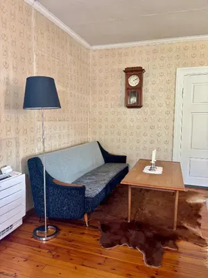 a living room with a couch and a table and a clock at Apotekbygget in Nesbyen