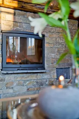 a stone wall with a fireplace with a television at Large family cabin in Hafjell ski in-out, BBQ, terrace and fireplace in Hafjell