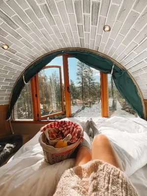 a person laying on a bed with a basket of fruit at Eventyrhyttene i Jotunheimen in Stuttgongfossen