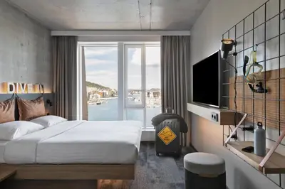 a hotel room with a bed and a large window at Moxy Bergen in Bergen
