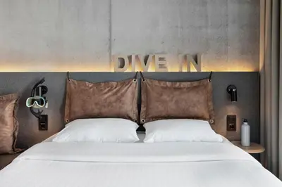 a bed with two pillows and a sign that reads drive in at Moxy Bergen in Bergen