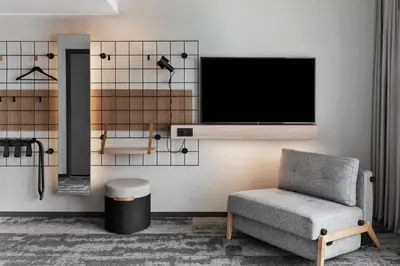a living room with a chair and a flat screen tv at Moxy Bergen in Bergen