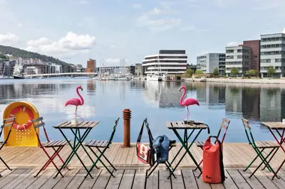 a group of chairs and tables and flamingos on a dock at Moxy Bergen in Bergen