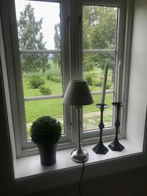 a window sill with a lamp and a candle at Drengstua på Dahl Østre in Stange