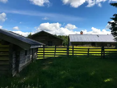 an old barn and a fence in a field at Drengstua på Dahl Østre in Stange