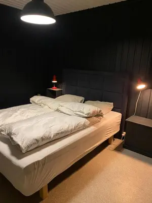a bedroom with a white bed with a black wall at Nordre Fossheim Gård Hemsedal in Hemsedal
