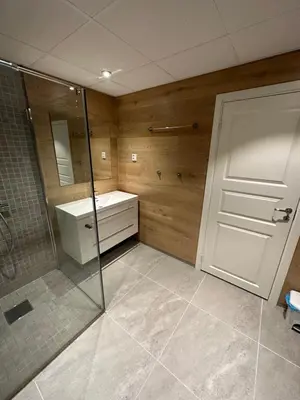 a bathroom with a shower and a sink and a glass door at Lom Apartment in Lom