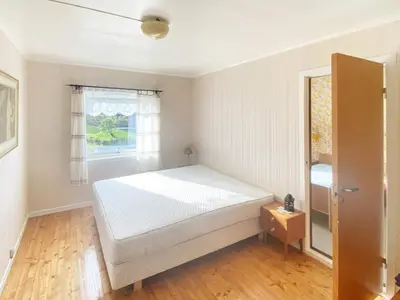 a bedroom with a white bed and a window at 10 person holiday home in Brekke in Brekke