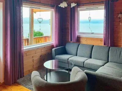 a living room with a couch and a table and two windows at 6 person holiday home in Brekke in Brekke