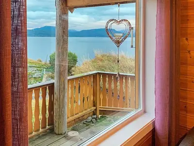 a heart window with a view of the water at 6 person holiday home in Brekke in Brekke