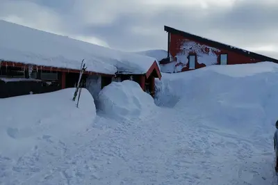 a house covered in snow next to a building at Stor barnevennlig leilighet in Hovden
