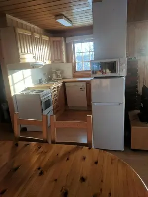 a kitchen with white appliances and a wooden floor at Toppen in Flatåker