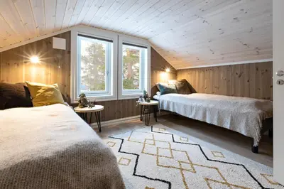 a bedroom with two beds and two windows at Lykkeli in Stranda