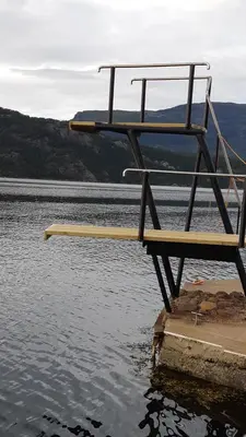 a bench sitting in the water next to a body of water at Teigen Leirstad, feriehus og hytter in Eikefjord